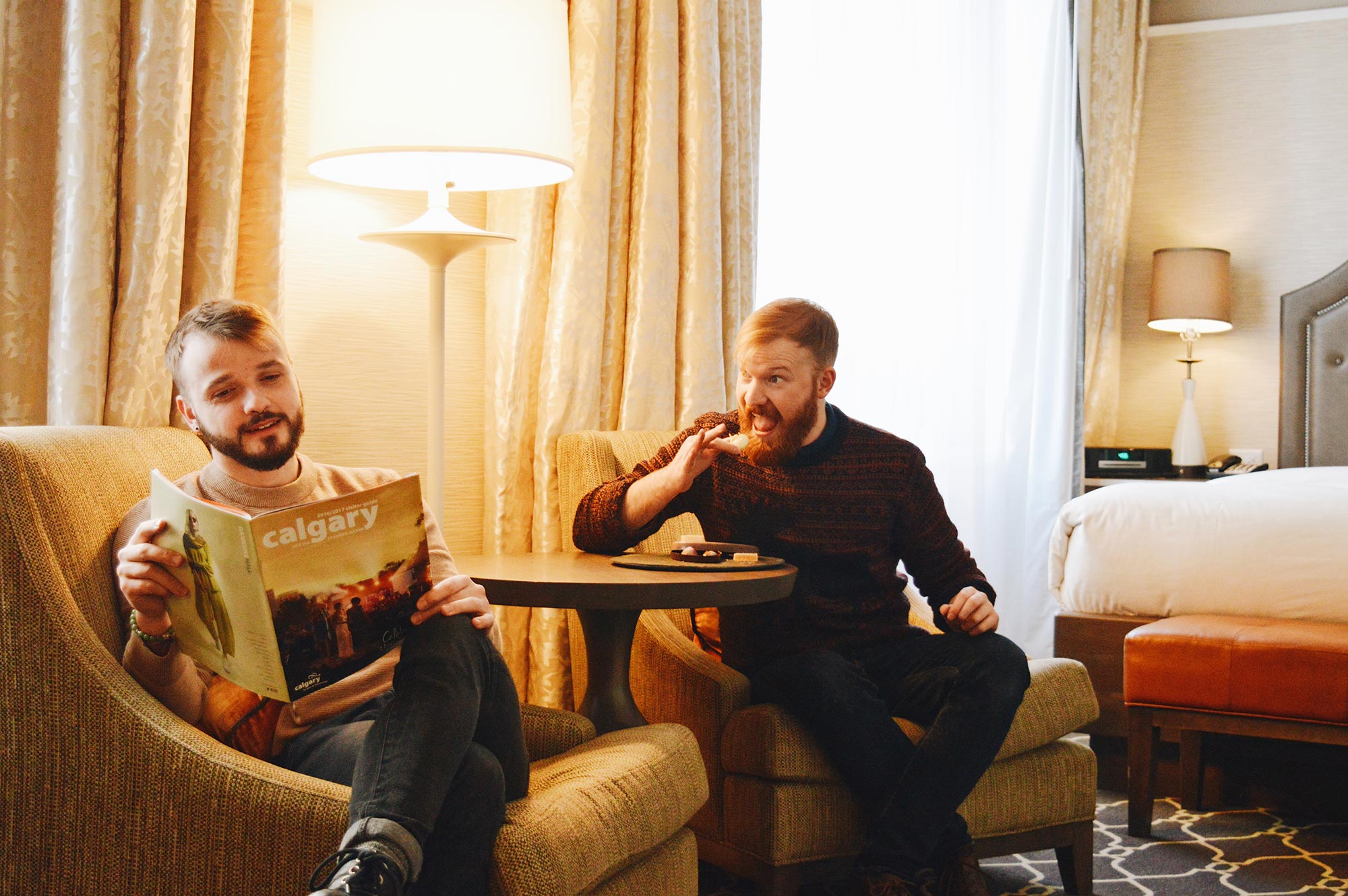 Karl reading about Calgary while Daan secretly eats all sweets | Gay-friendly Fairmont Palliser Hotel Downtown Calgary © CoupleofMen.com