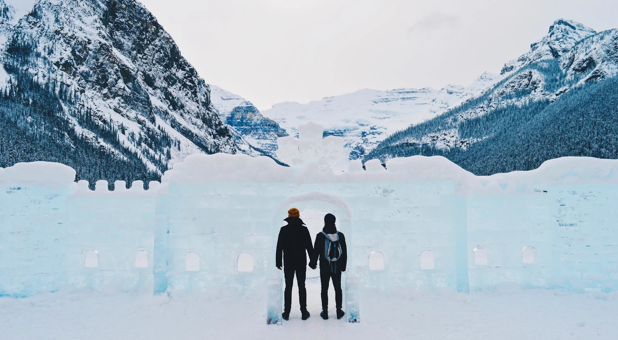 Karl & Daan hand-in-hand in front of the frozen Lake Louise | Winter Road Trip Alberta Highlights Canadian Rocky Mountains © Coupleofmen.com