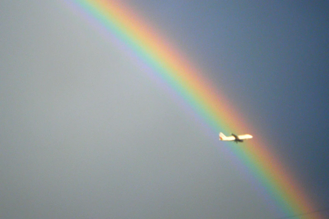Ein Flugzeug vor einem knallig bunten Regenbogen | US Airlines Gender Neutral Buchungsoption © Coupleofmen.com