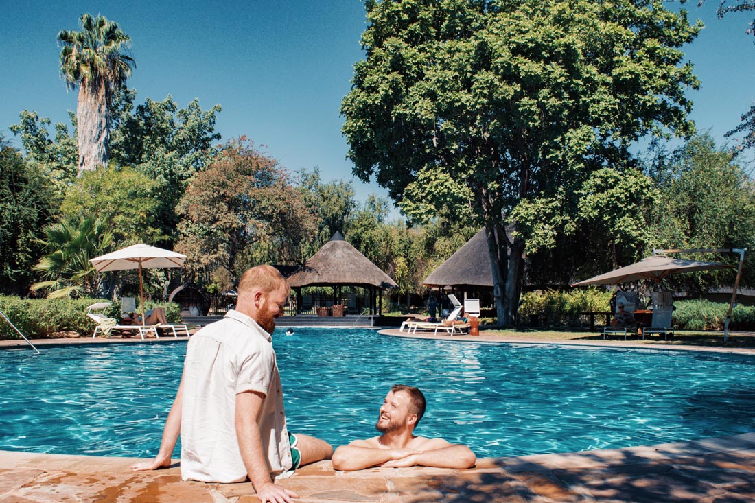 Gay Couple Travel Blogger having a refreshing swim in the pool at Mokuti Lodge at the East Gate of Etosha in Namibia © Coupleofmen.com