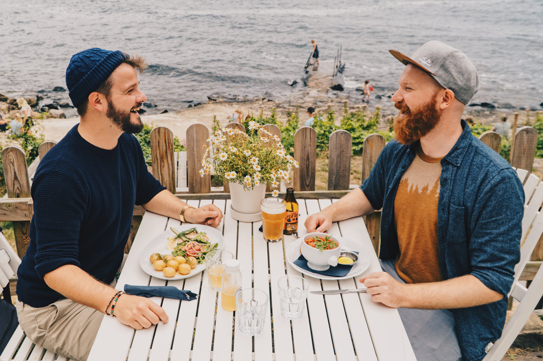 Gay Couple laughing and enjoying Lunch with View of Ransvik 'Sin of Molle' © Coupleofmen.com