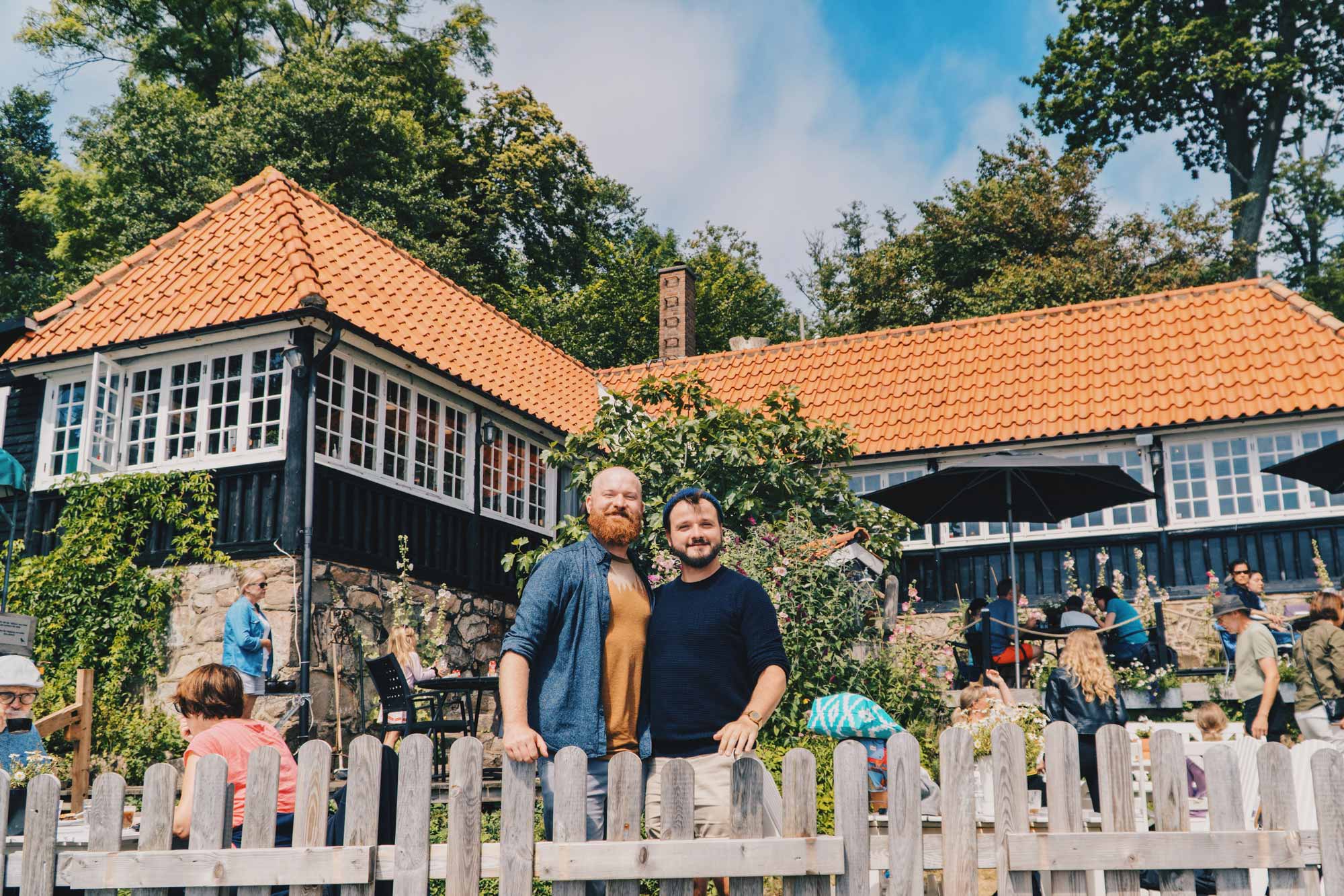 Gay-owned Café Ransvik Havsveranda Arm-in-Arm in front of Café Ransvik Havsveranda owned and operated by gay couple Matti & Andy © Coupleofmen.com