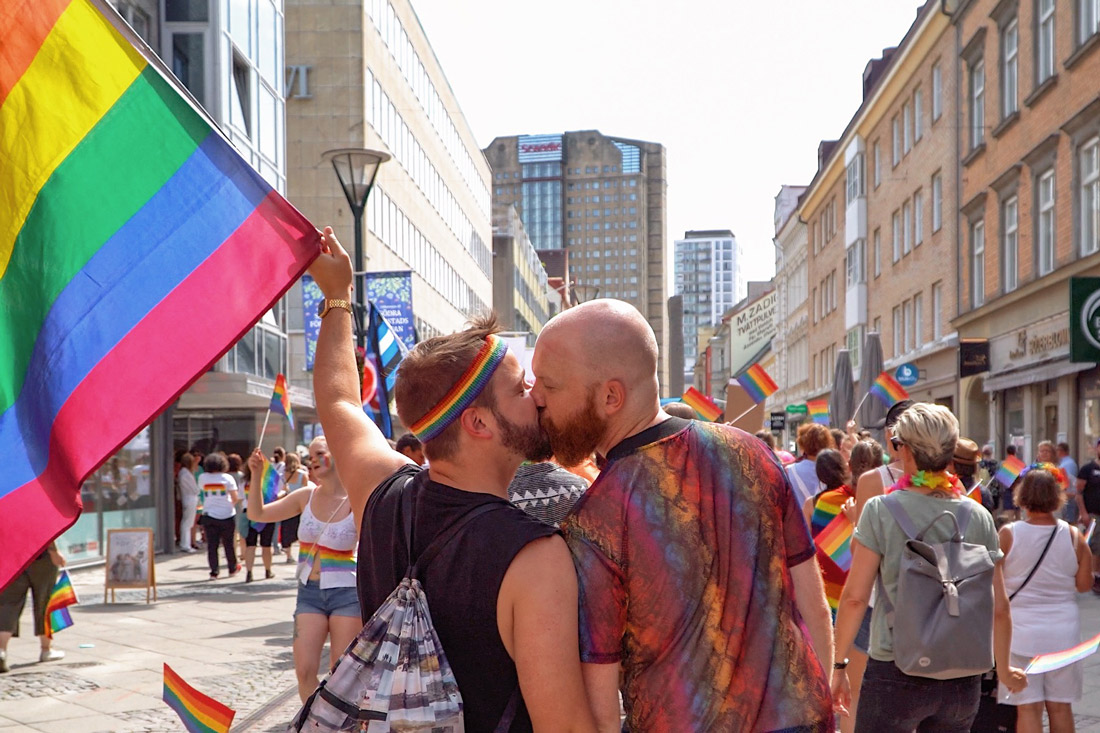 Gay Pride Malmö 2019 Proudly waving the rainbow flag and giving each other a gay kiss during Malmö Pride 2019 © Coupleofmen.com