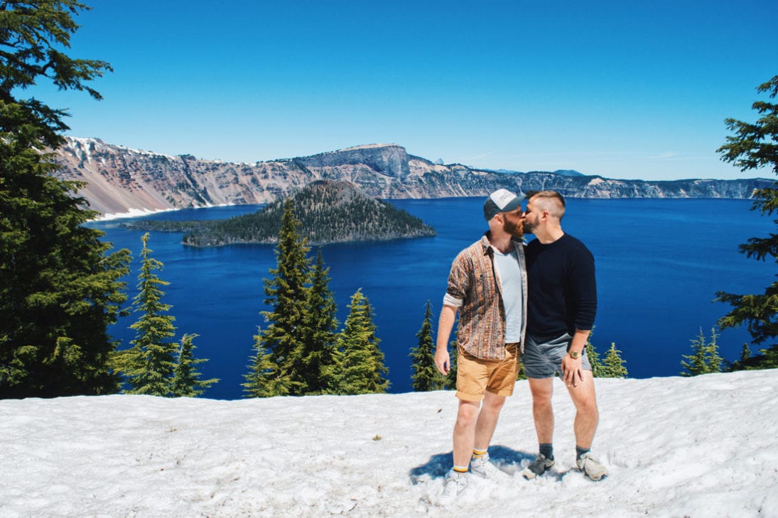 A snowy kiss in June at the deep blue Crater Lake in gay-friendly Oregon | Gay Oregon Travel Journal © Coupleofmen.com