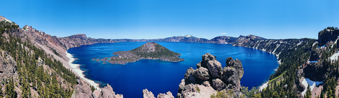 Panorama photo of the deep blue Crater Lake in Oregon in June with summer weather and blue sky © Coupleofmen.com