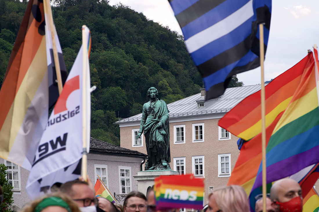 LGBTQ+ freundliche Salzburg CSD Salzburg Pride Rainbow Pride Flags in front of Mozart statue © Coupleofmen.com