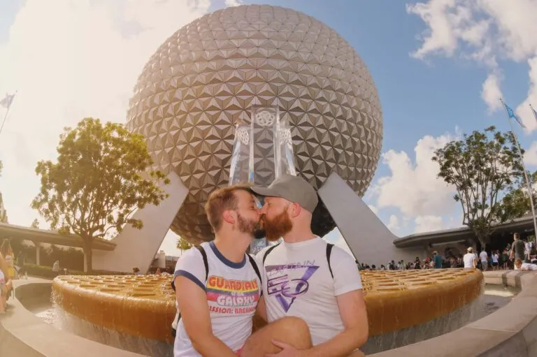 A gay couple of men kissing in front of Spaceship Earth in EPCOT at the Walt Disney World Resort in Orlando.
