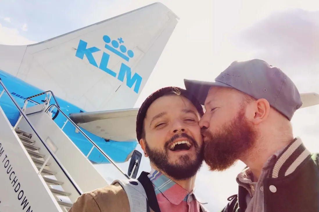 A kiss in front of an KLM Royal Dutch Airline plane in Amsterdam Schiphol © Coupleofmen.com