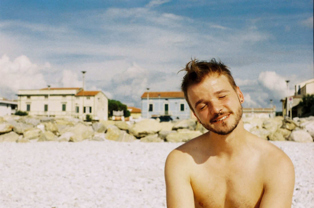 Gay Traveler Karl exploring Italy sitting at the beach in Pisa © Coupleofmen.com
