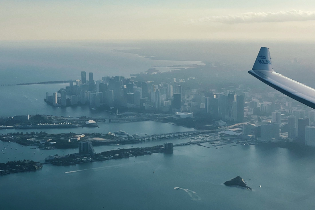 Flying with KLM from Amsterdam to Miami: KLM wing over Miami, Florida just after takeoff, above the city's coast © Coupleofmen.com