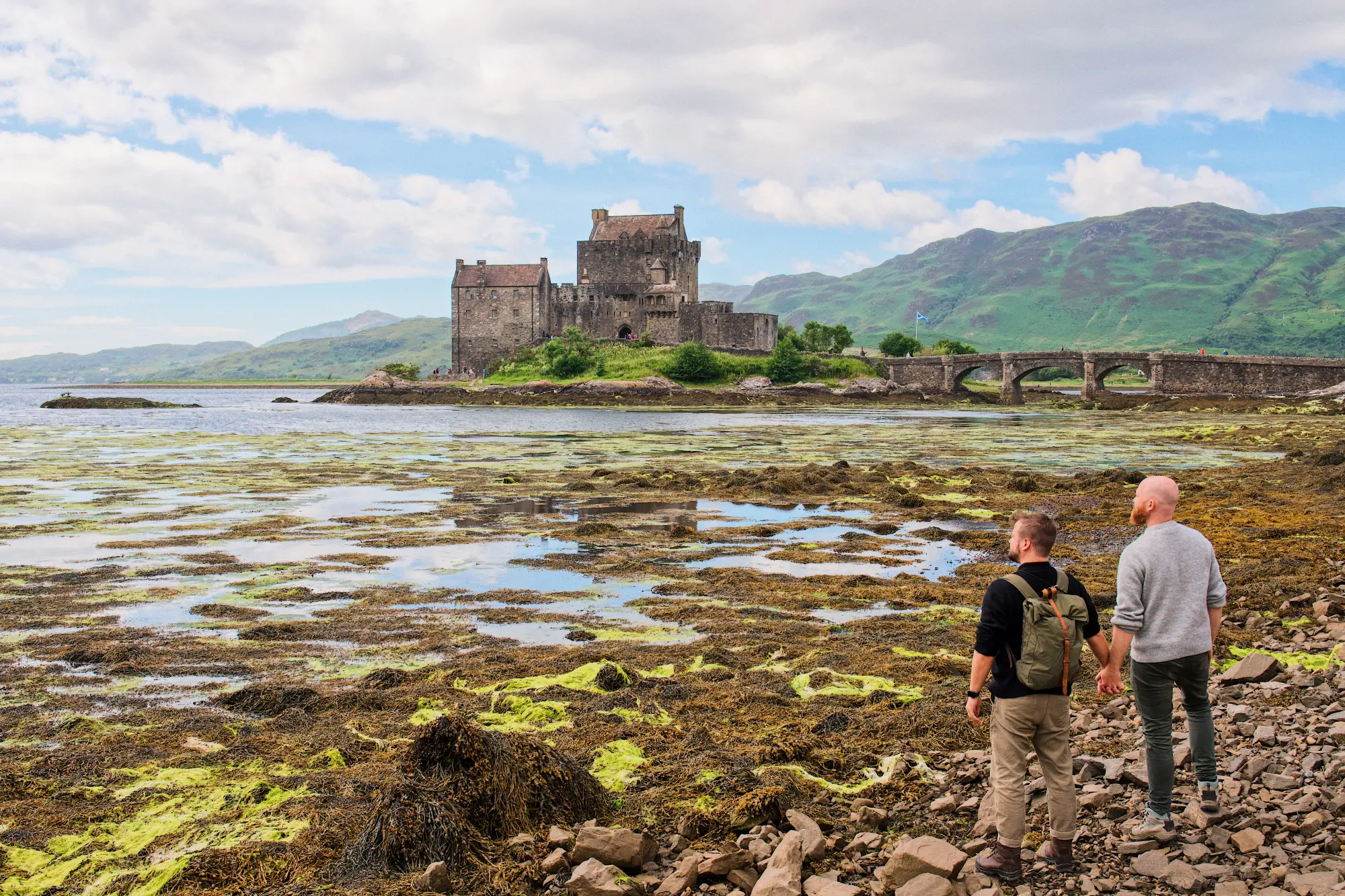 Scotland at its best! Hand in hand in front of Eilean Donan Castle in Donnie © Coupleomen.com