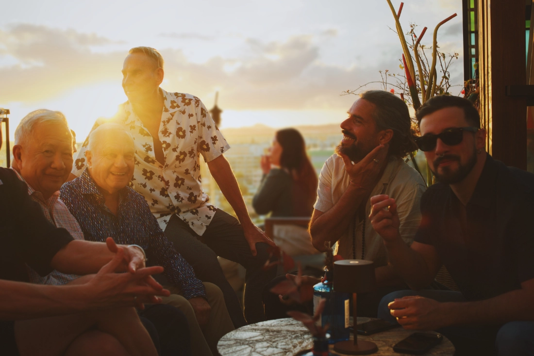 A group of men having cocktails at a rooftop restaurant during sunset