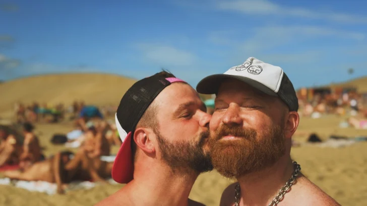 Karl kissing Daan at the Maspalomas Gay Beach while wearing caps and nothing else