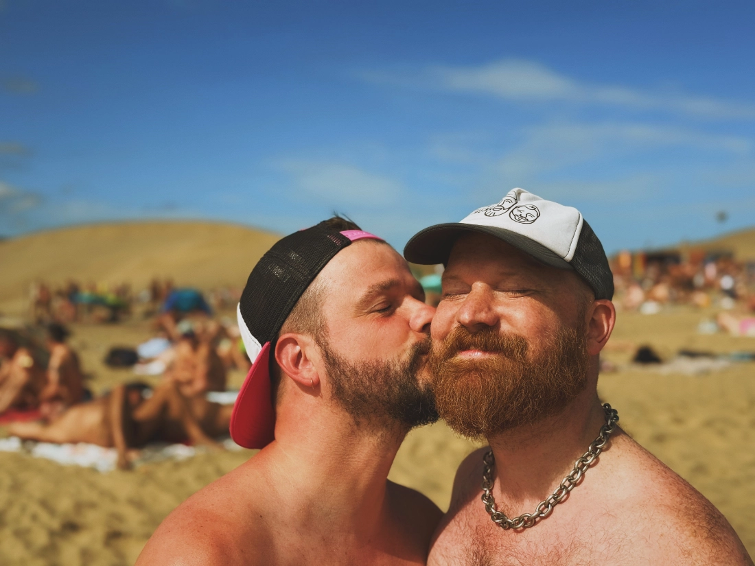 Karl kissing Daan at the Maspalomas Gay Beach while wearing caps and nothing else