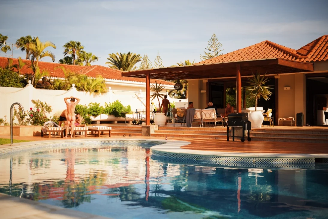 A villa on Gran Canaria with in front of it a pool and seven naked men hanging out. Clothing-optional Gay Vacation Gran Canaria