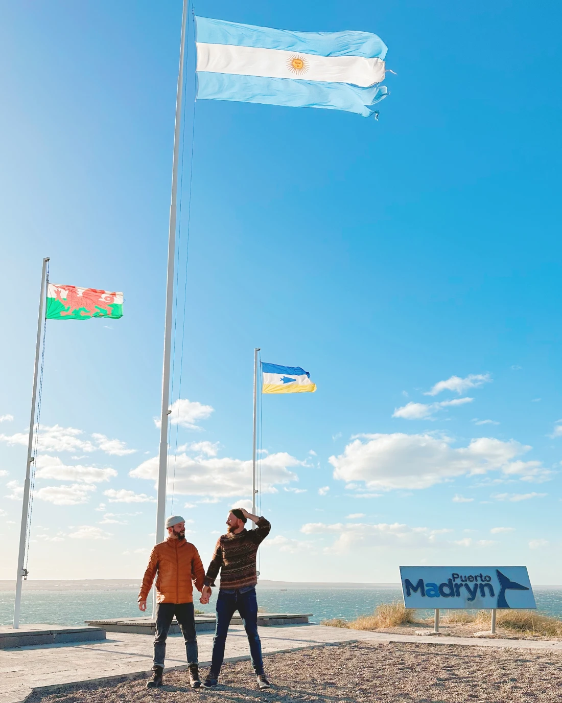 Windy selfie in Puerto Madryn with the flags high above us © Coupleofmen.com gay couple Puerto Madryn