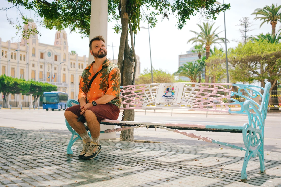 Karl taking a break on the bench colored in the trans flag in Melilla &copy; Coupleofmen.com