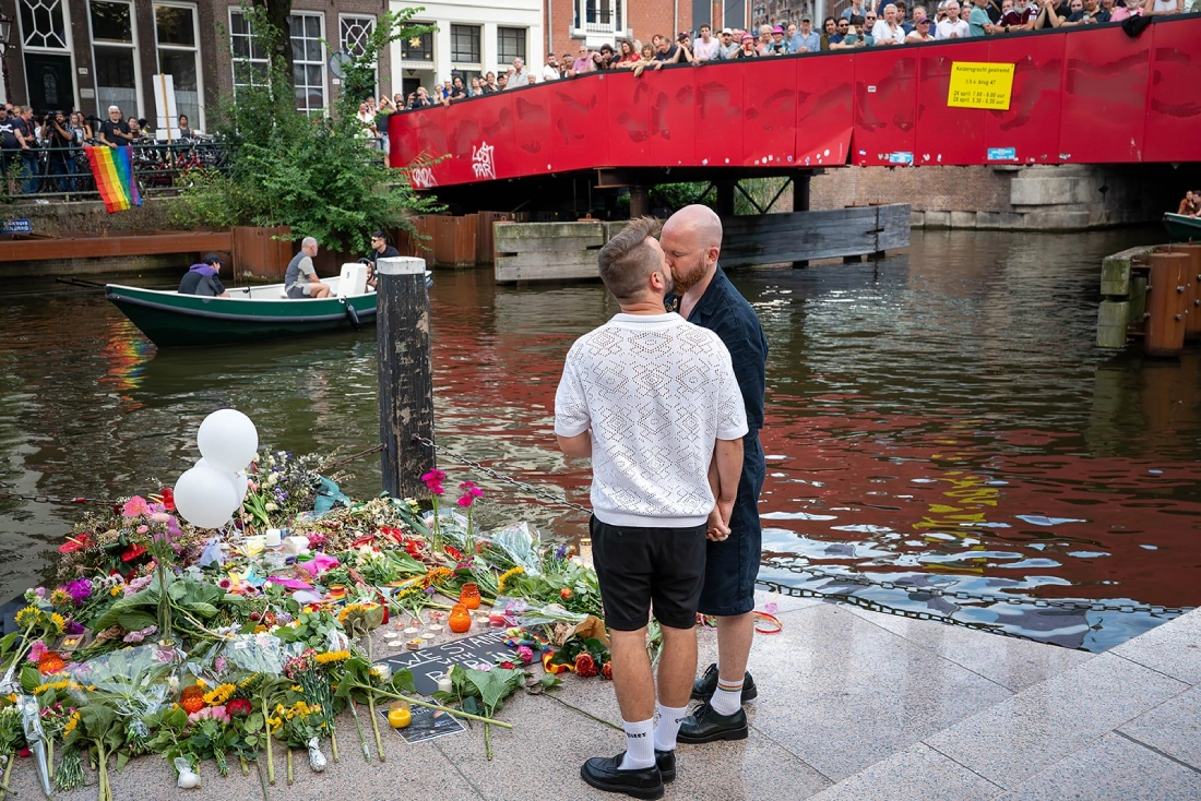 Karl and Daan laying down flowers and kiss at Homomonument Amsterdam