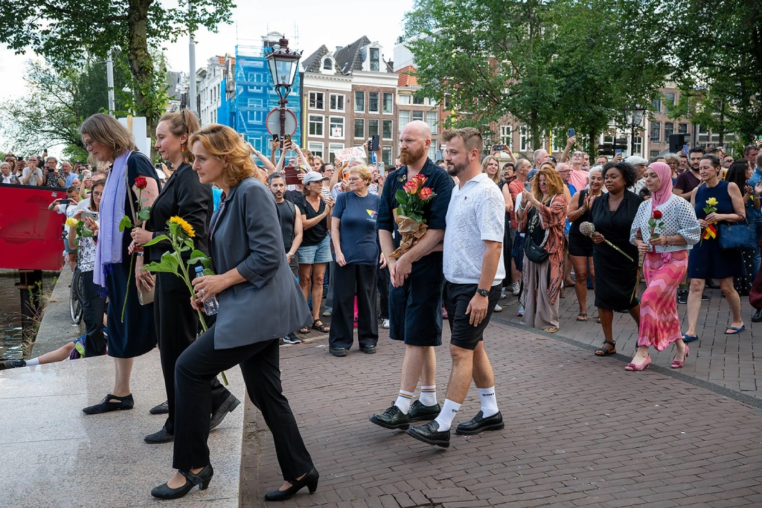 Walking to lay down flowers on the Homomonument: Karl and Daan hand in hand, following Myrtille Danse, leader of the COC